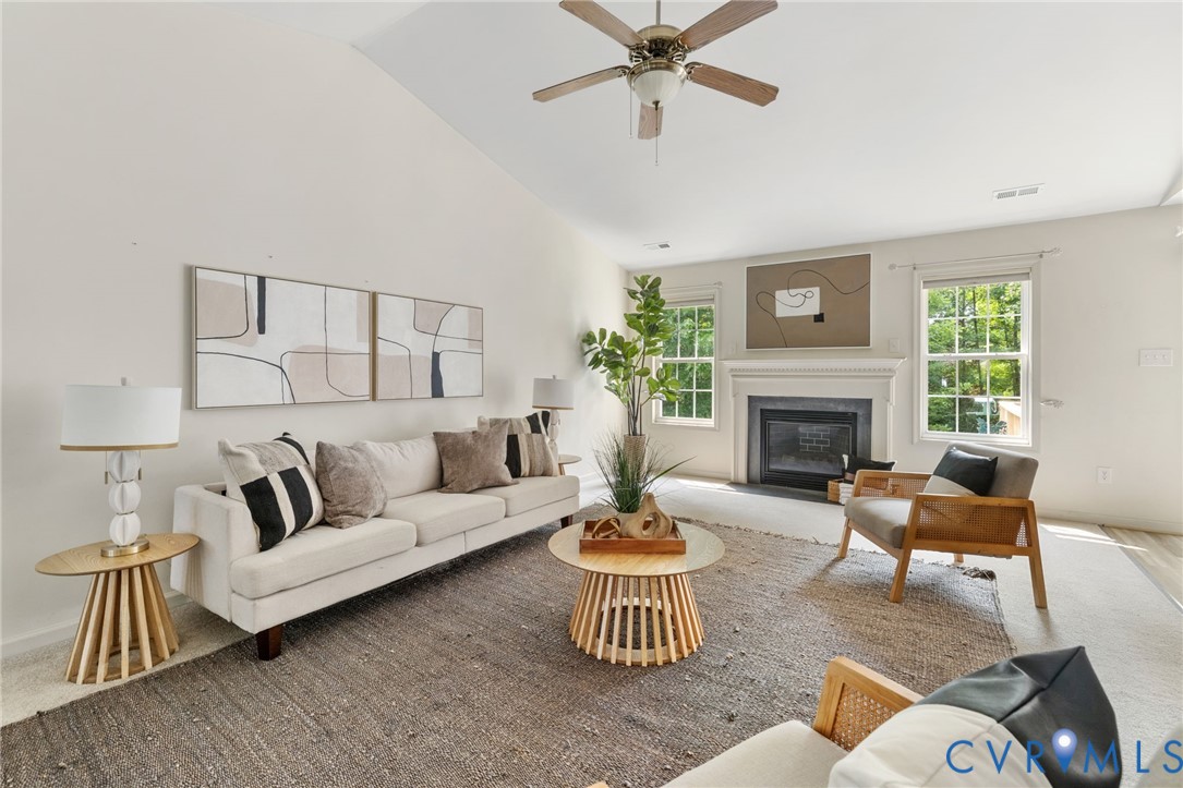 Vaulted ceiling, ceiling fan, fireplace with mantel, double windows, and wood-finish flooring