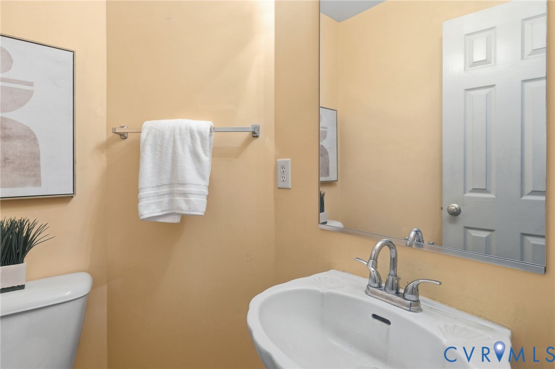 Pedestal sink with chrome-finish faucet, wall-mounted mirror, and paneled door