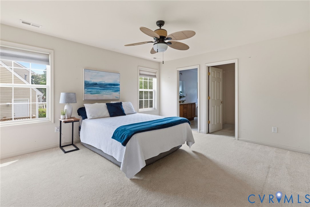 Wall-to-wall carpeting, two windows, and a ceiling fan with integrated lighting