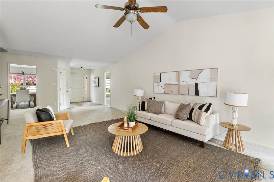 Vaulted ceiling with ceiling fan, light-colored wall paint, white trim, and a white paneled entry door