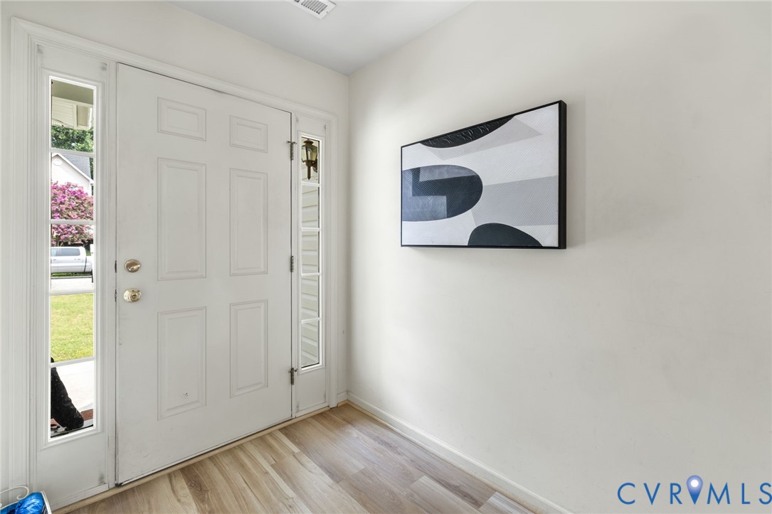 Entryway featuring a paneled door with glass sidelights and wood-finish flooring