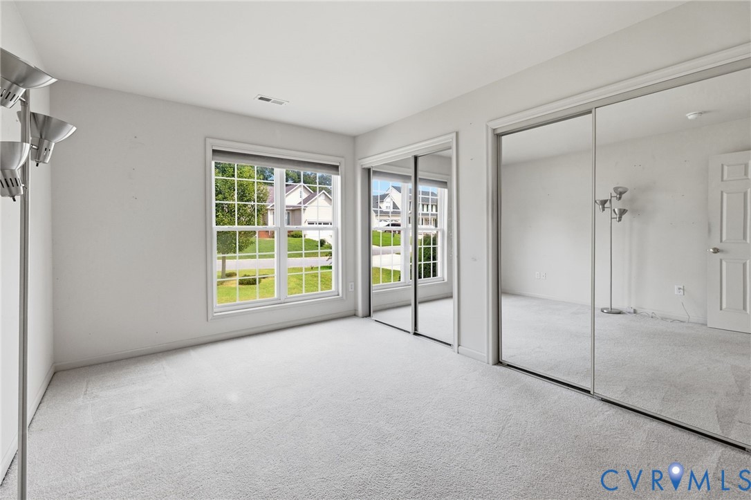 Wall-to-wall carpeting, multiple windows providing natural illumination, and mirrored closet doors