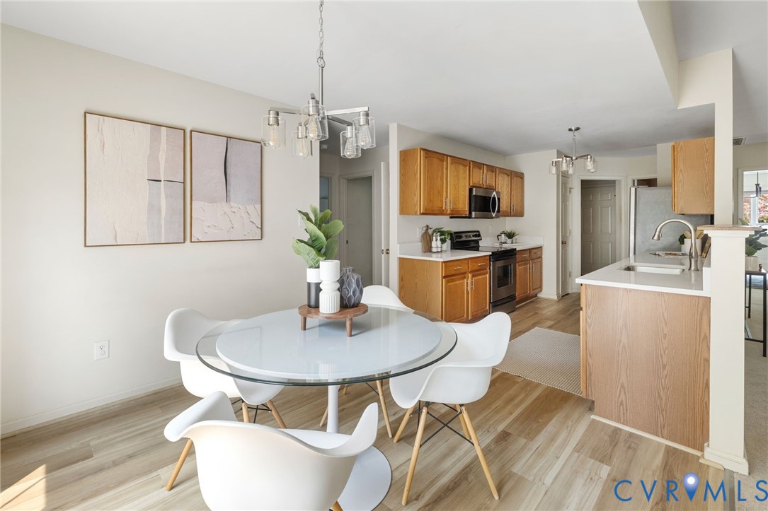 Hardwood-finish flooring, recessed lighting, and a kitchen featuring wood cabinetry, stainless steel appliances, and a peninsula with countertop seating