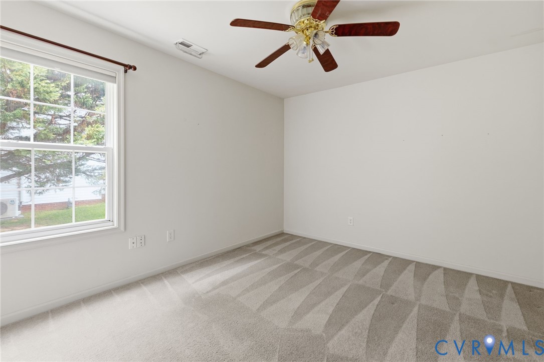 Neutral carpeting with visible pattern, white walls, and a ceiling fan with wood-finish blades