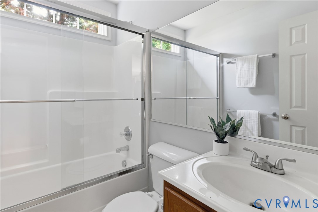 Built-in white bathtub with sliding glass enclosure, chrome fixtures, and an integrated window