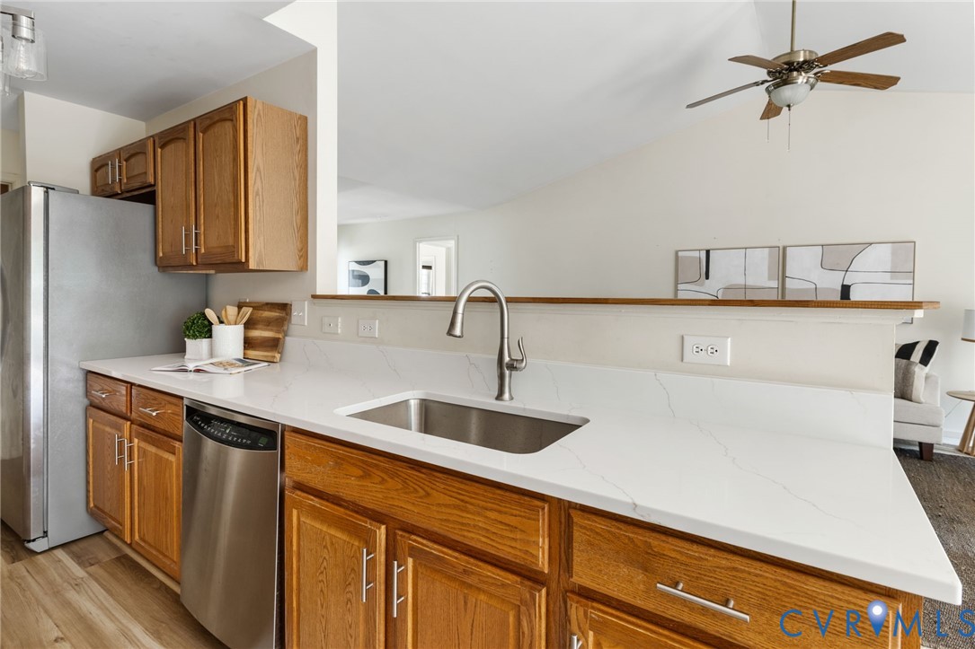 Kitchen featuring stainless steel appliances, wood-finish cabinetry, a stainless steel sink, and light-toned countertops
