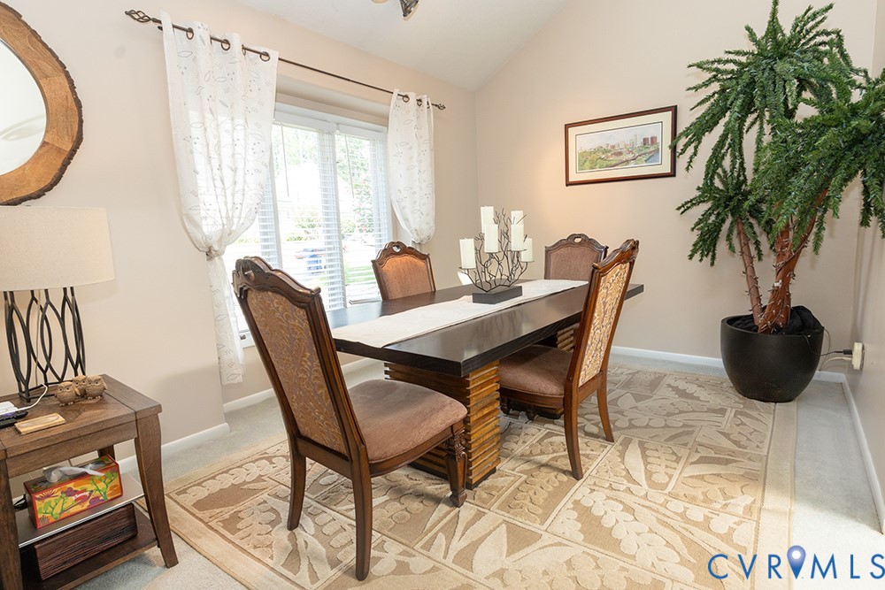 Vaulted ceiling, window with white blinds, neutral wall paint, and wood-finish flooring