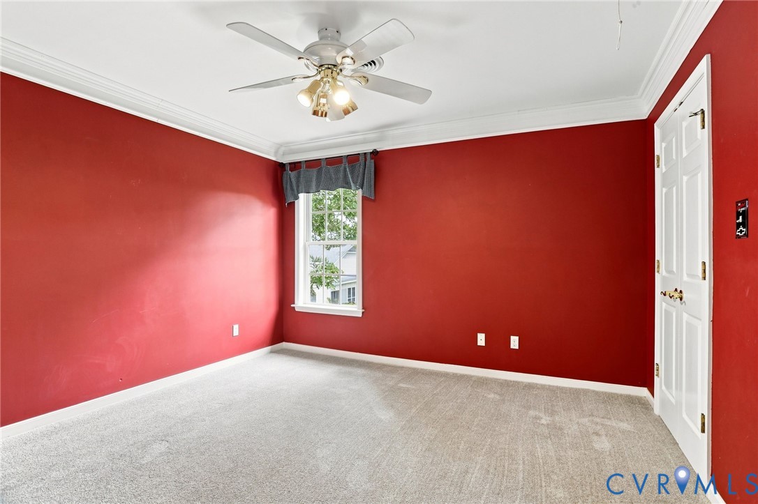 Bright fourth bedroom with crown molding, ceiling fan, and closet storage.