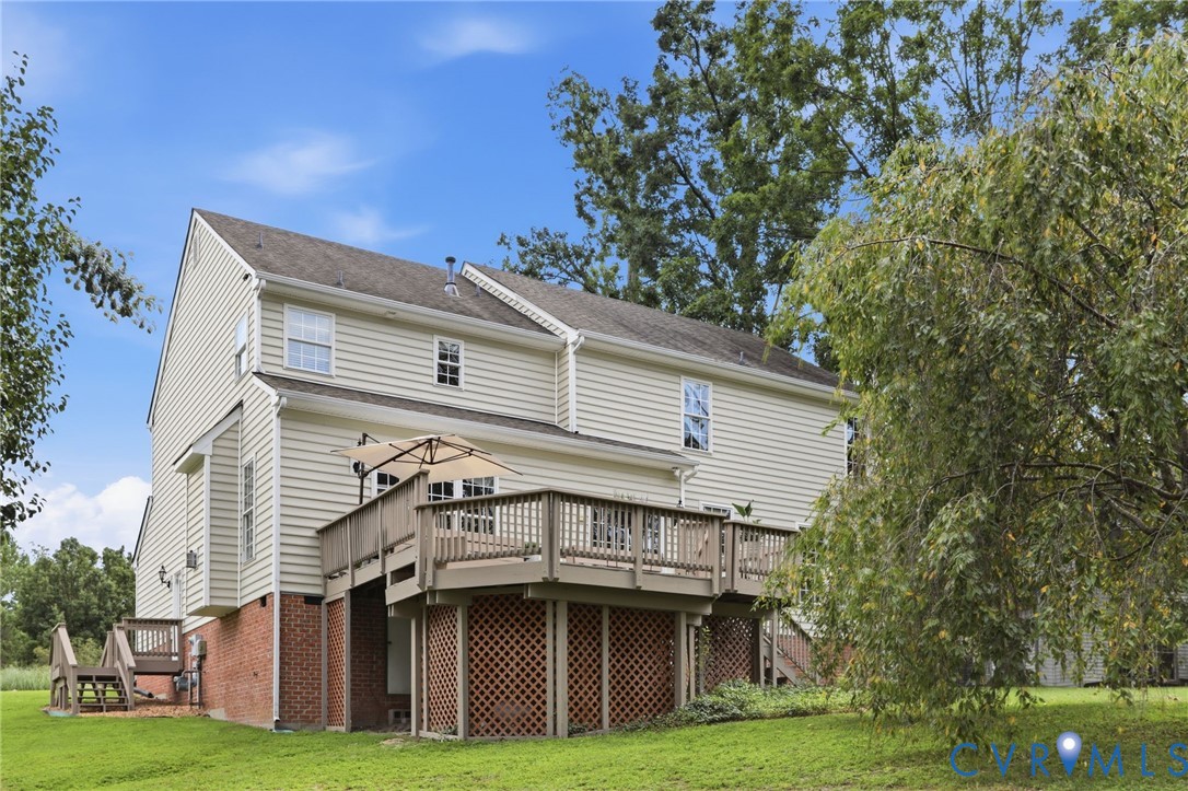 Rear view of the home highlights the spacious elevated deck overlooking the backyard.
