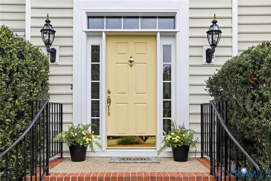 Welcoming front entrance features sidelights, classic brick steps, and mature landscaping.