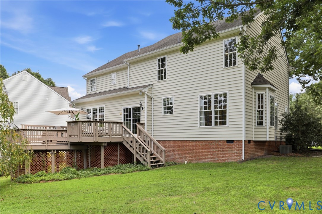 Another view of the home showcases the large deck, rear yard, and abundance of windows.