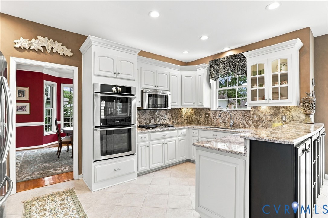 Spacious kitchen features white cabinetry, granite countertops, double ovens, stainless steel appliances, and abundant storage and prep space.