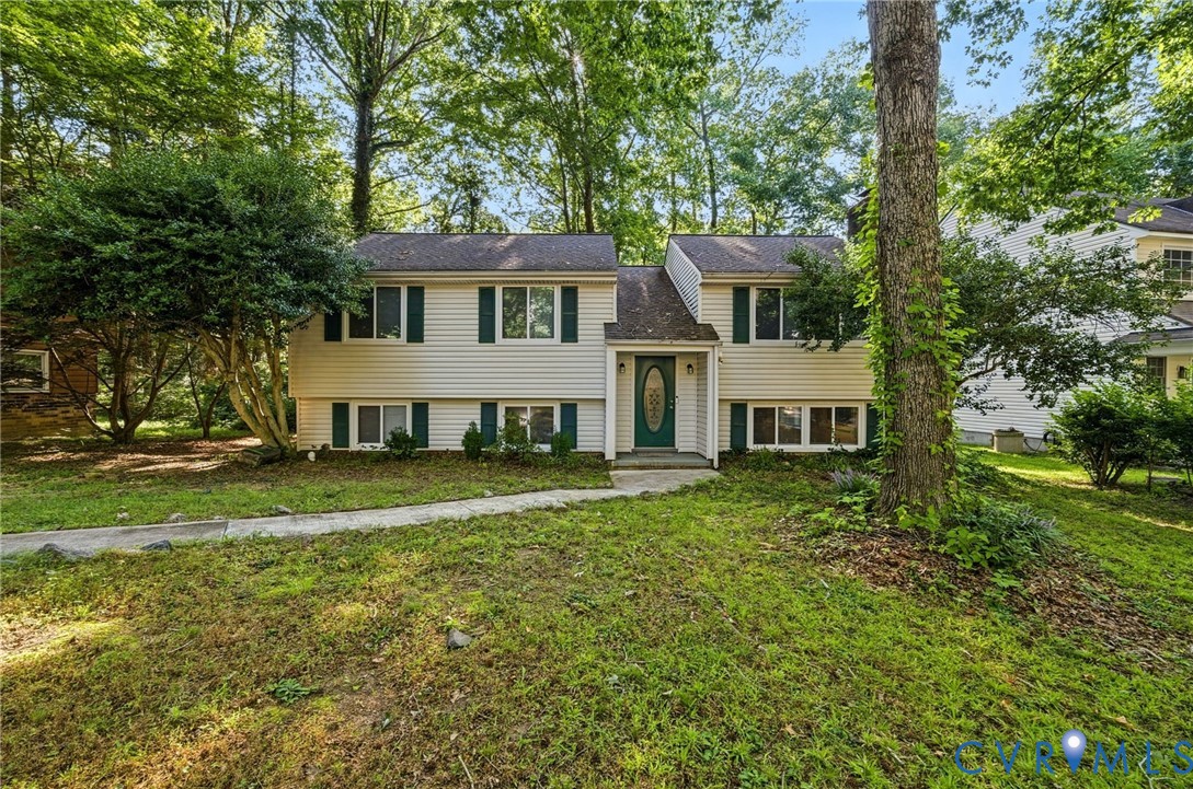 Split-level residence featuring light-colored siding, dark shutters, and a prominent front entry with an oval glass insert door