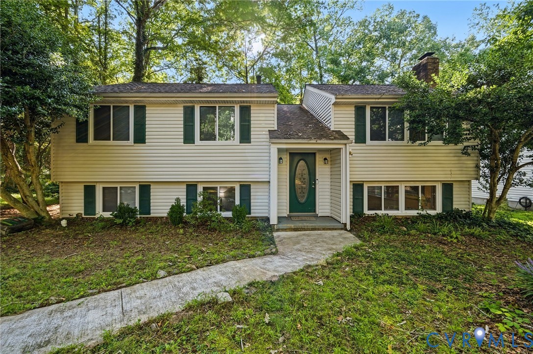 Split-level home featuring light-colored siding and green shutters