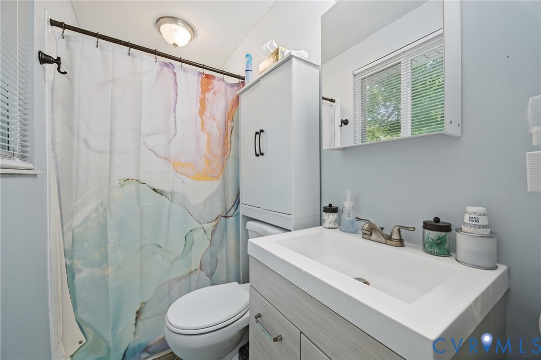 Built-in vanity with integrated sink, wall-mounted mirror, window with blinds, and flush-mount ceiling light