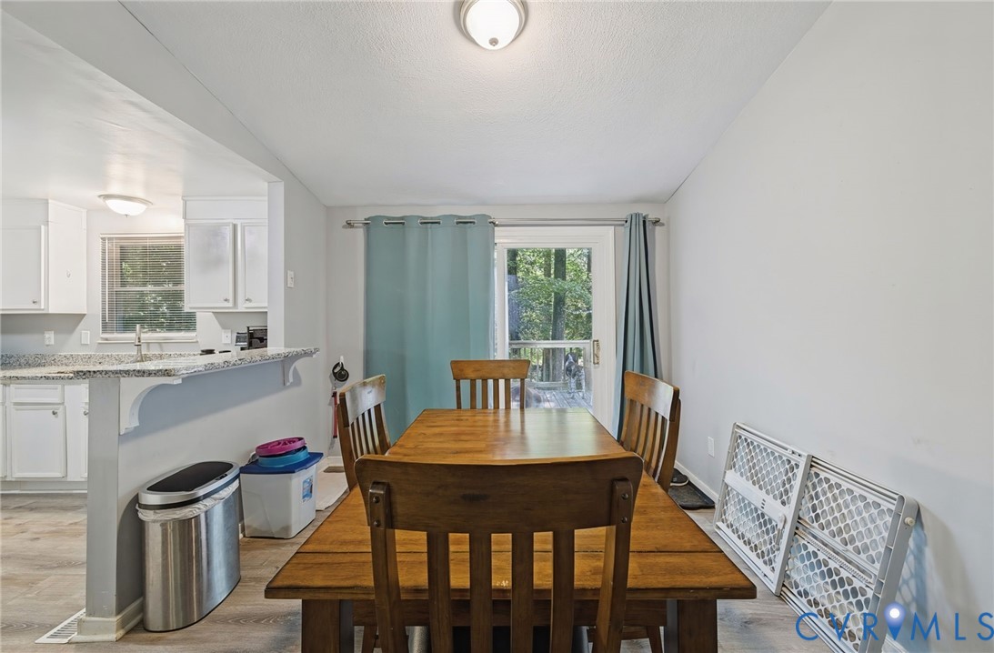 Dining area with light-toned flooring, featuring a kitchen pass-through and a sliding glass door