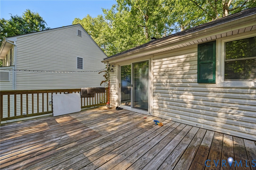Spacious wooden deck with a slatted railing, siding exterior, and sliding glass door access