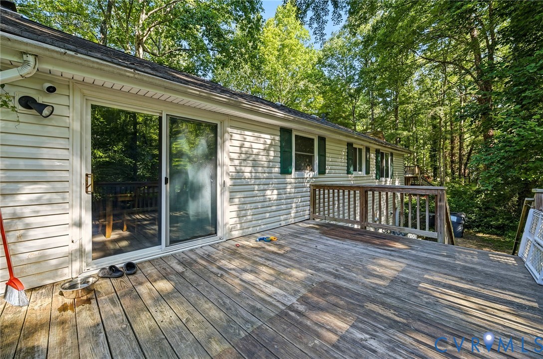 Expansive exterior deck featuring a wooden railing and mature trees