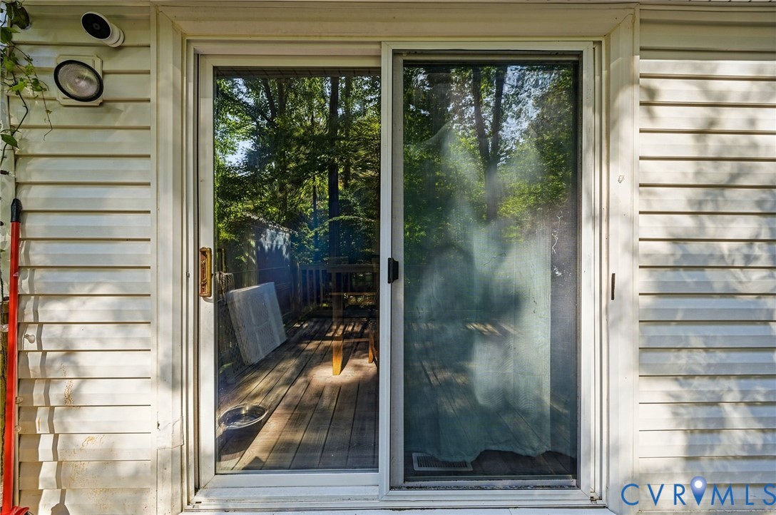 White vinyl siding exterior with a sliding glass door and an exterior light fixture