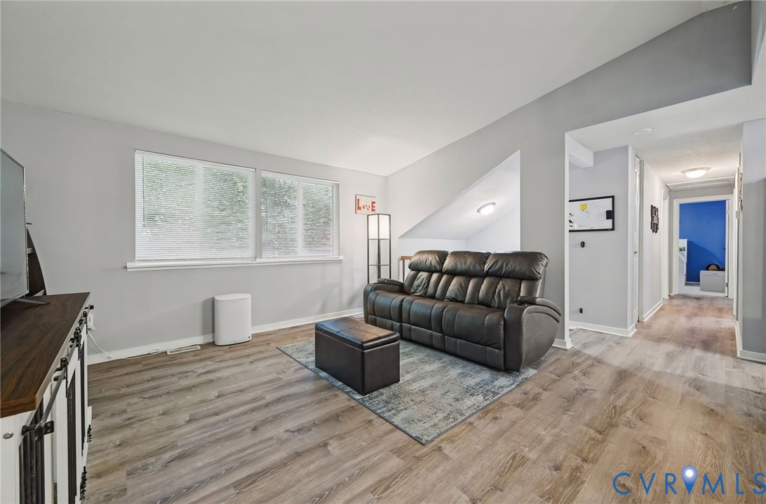 Wood-finish flooring throughout, two windows with white blinds, and a built-in media console with barn door accents