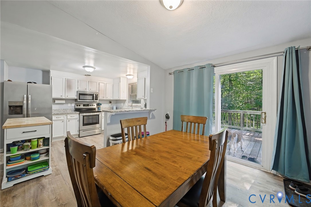 Open-concept dining area with wood-finish flooring, a sliding glass door, and recessed lighting