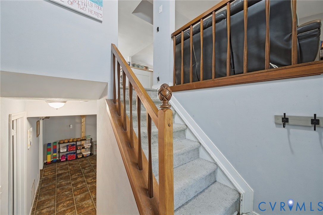 Carpeted staircase with wood railing and finial newel post