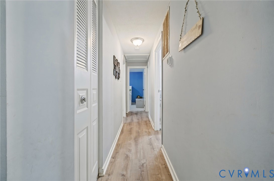 Hallway featuring wood-finish flooring, white walls, and a flush mount ceiling light