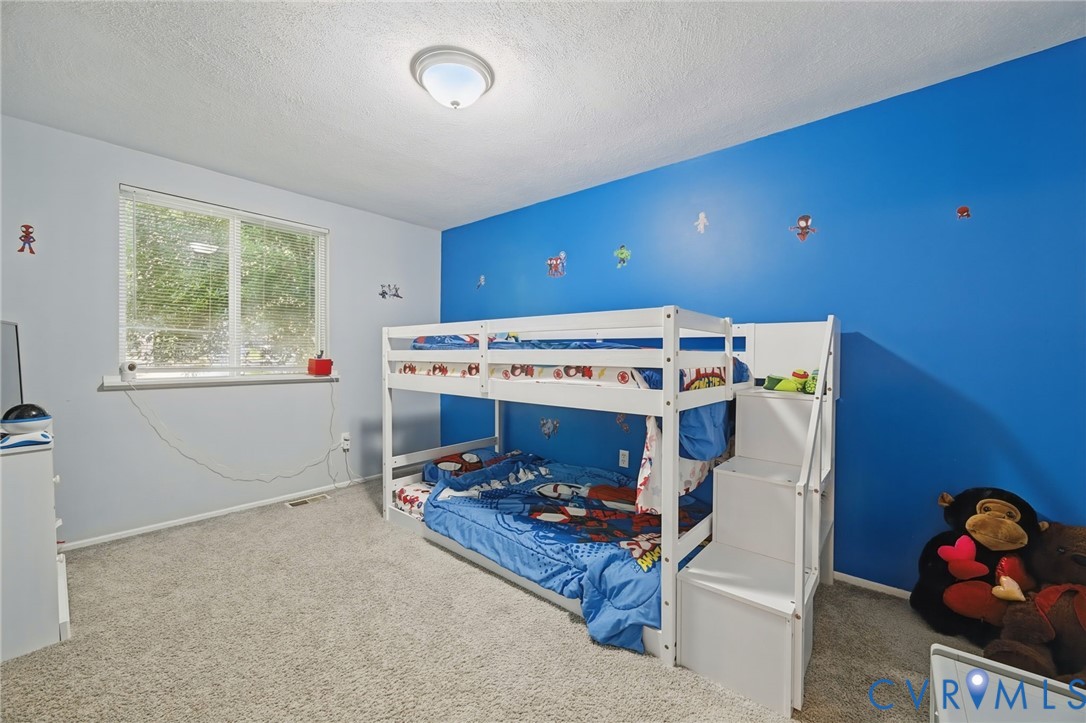 Recessed ceiling light fixture, white walls with an accent wall, window with natural light, and plush carpet flooring