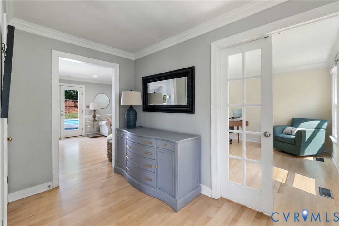 Light wood-finish flooring, crown molding, and a paneled glass French doors that lead to Office