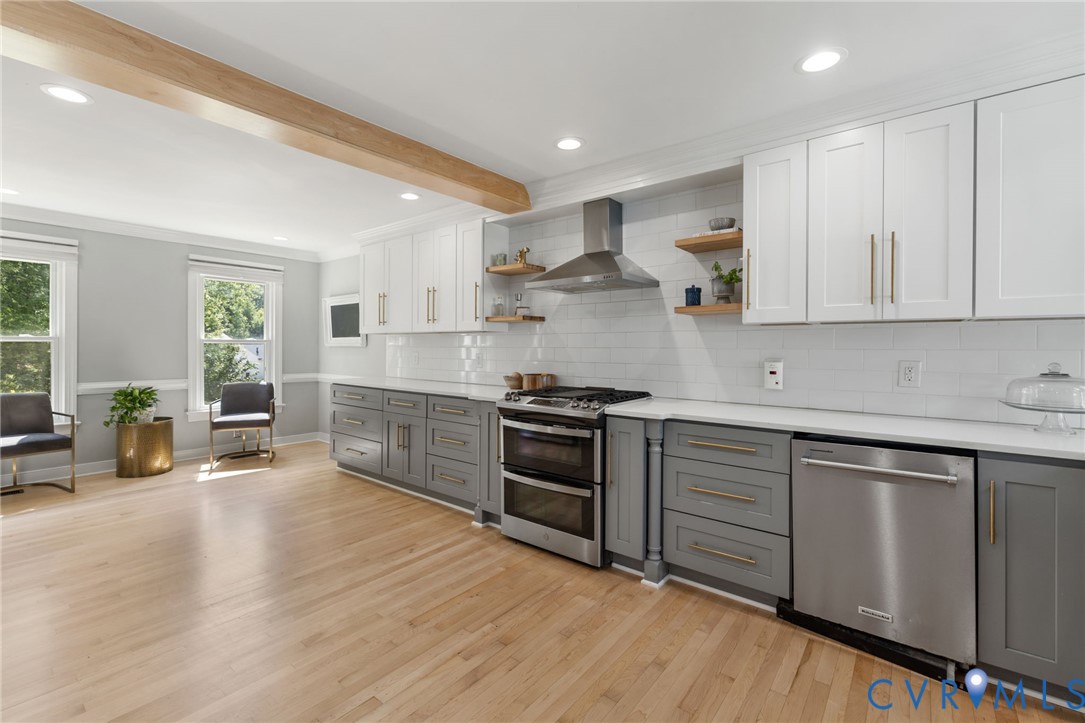 Kitchen featuring light wood-finish flooring, white upper cabinetry, gray lower cabinetry, white subway tile backsplash, and stainless steel appliances