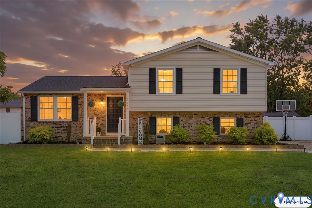 Split-level residence featuring brick and siding exterior, front entry porch, white railings, and black front door