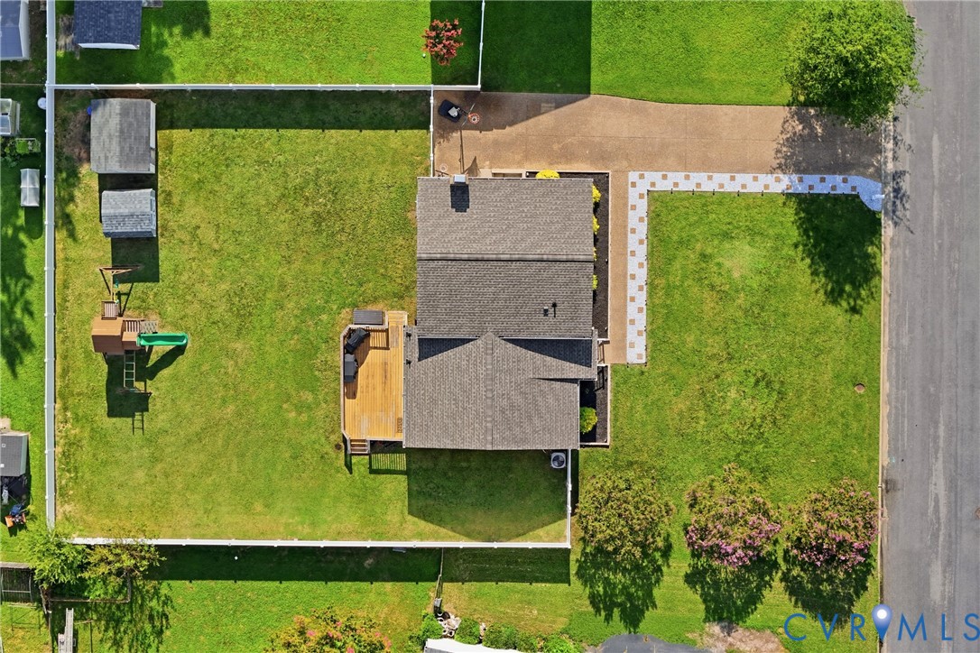 Expansive lot featuring a large deck, two storage sheds, a paved driveway, and a front walkway with square paver stones