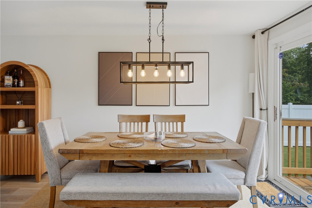 Modern linear chandelier over a wood-finish dining table with upholstered seating
