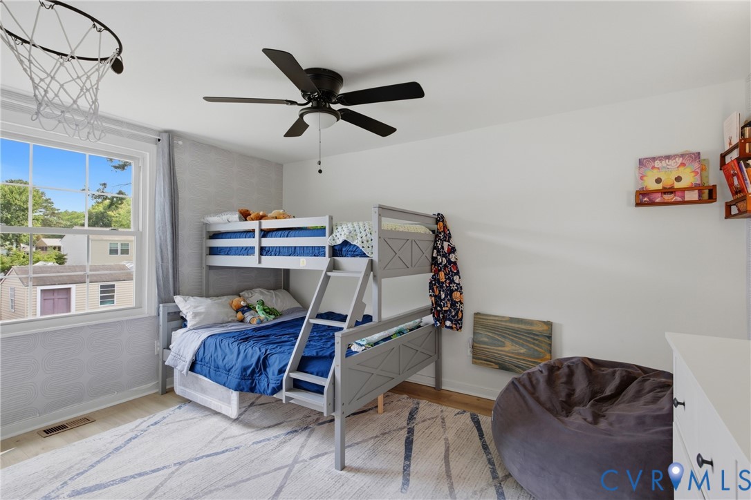 Bright room with a large window, light-toned wood-finish flooring, and a ceiling fan