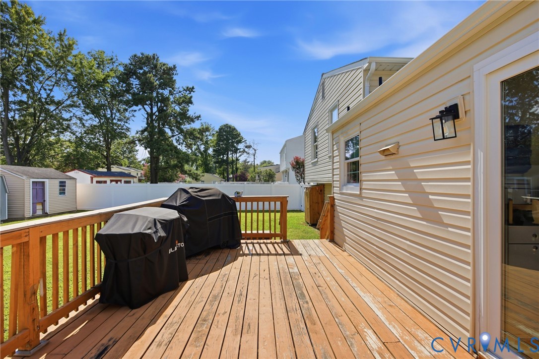 Spacious wood deck with railing overlooking a fenced yard and detached storage shed