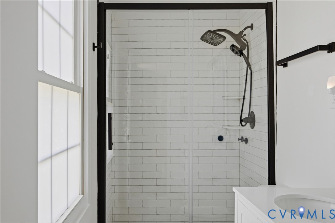 Shower enclosure with black framing, white subway tile surround, and a matte black shower system