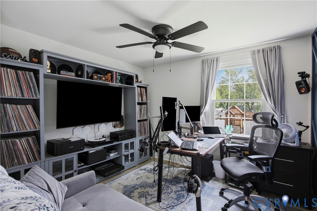 Built-in media console with open shelving, ceiling fan, large window, and light-toned walls