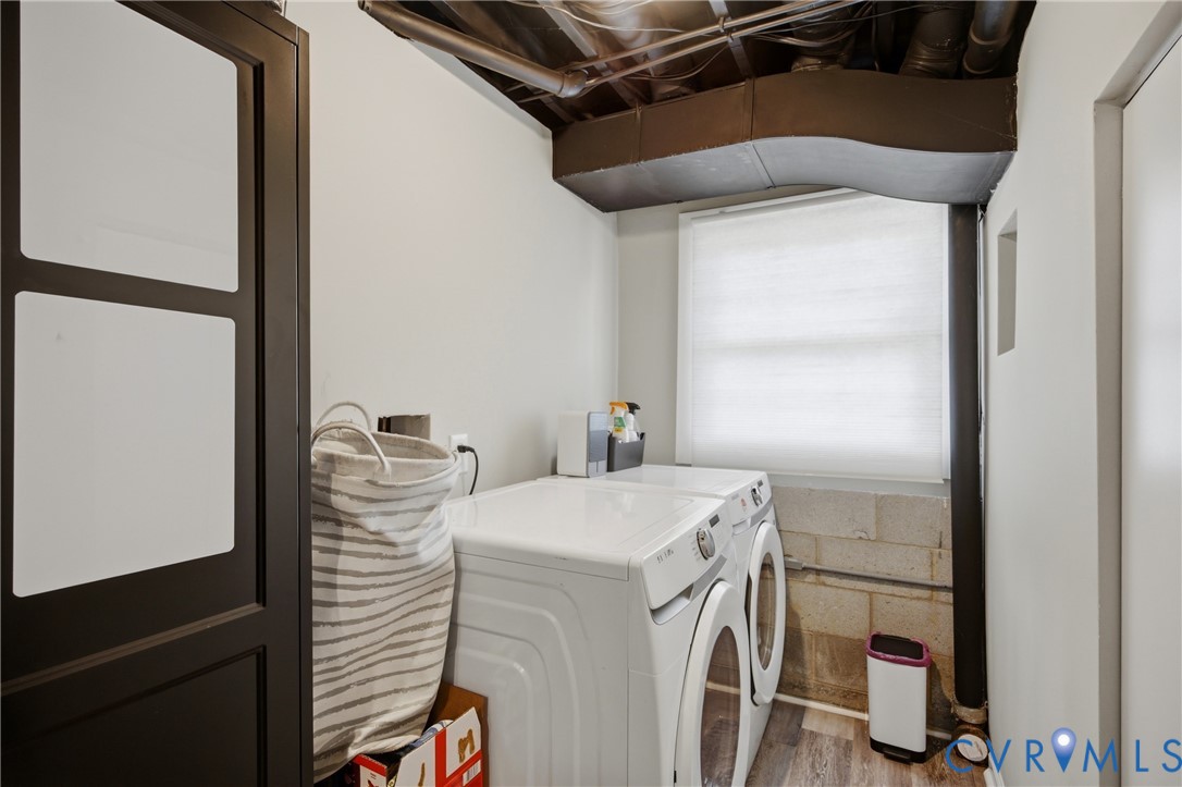 Laundry area featuring a window, wood-finish flooring, and exposed ceiling utilities