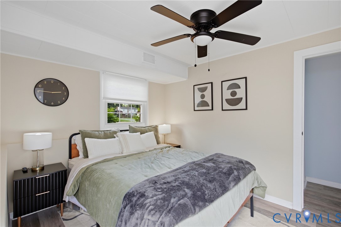 Ceiling fan with light fixture, window with white blind, light wood-finish flooring, white trim, and a door frame