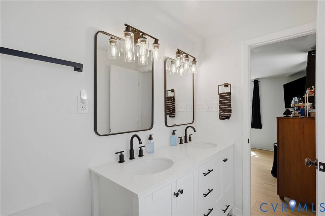 Dual vanity with white cabinetry, matte black hardware, and integrated sinks