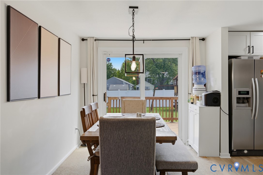 Dining area with wood-finish flooring, a contemporary pendant light fixture, and a sliding glass door providing access to an exterior deck