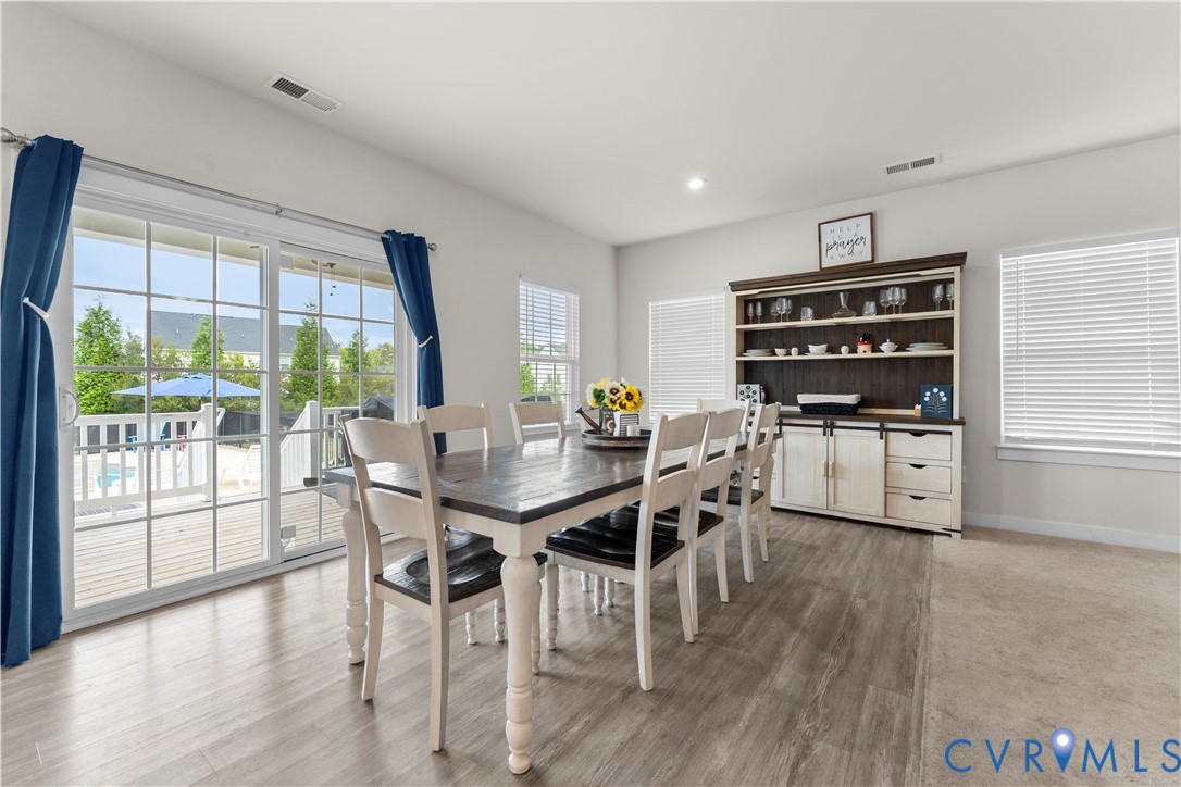 Sliding glass doors opening to an outdoor deck, recessed ceiling lighting, wood-finish flooring, and built-in shelving with lower cabinetry