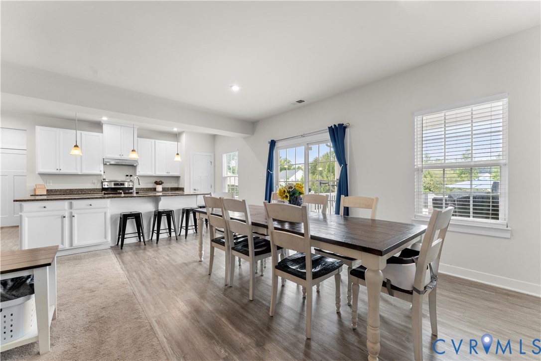 Open concept layout featuring wood-finish flooring, white cabinetry, dark countertops, and stainless steel appliances