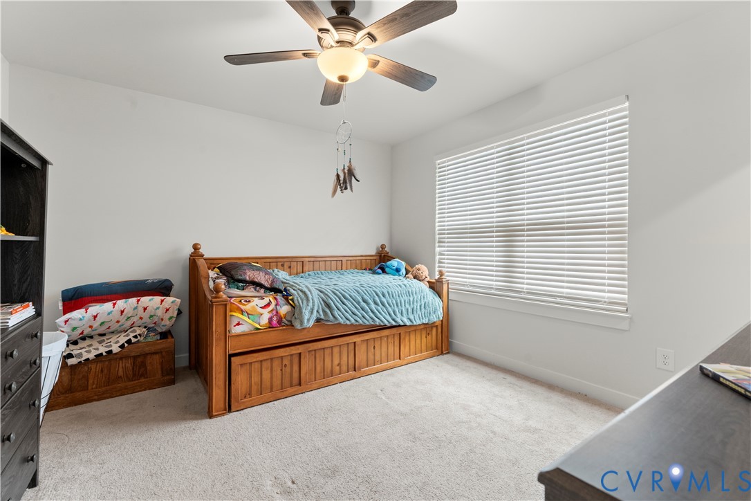 Light-colored carpeting, a ceiling fan with integrated lighting, and a window with horizontal blinds