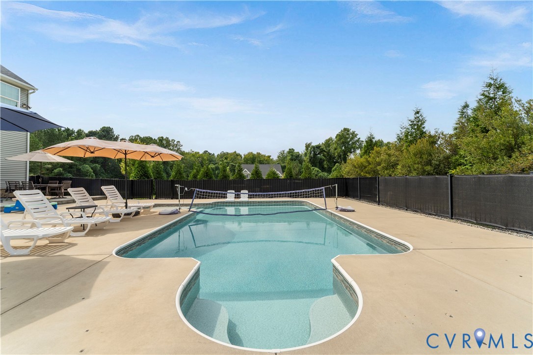 Backyard oasis featuring an in-ground swimming pool with surrounding concrete decking and privacy fencing