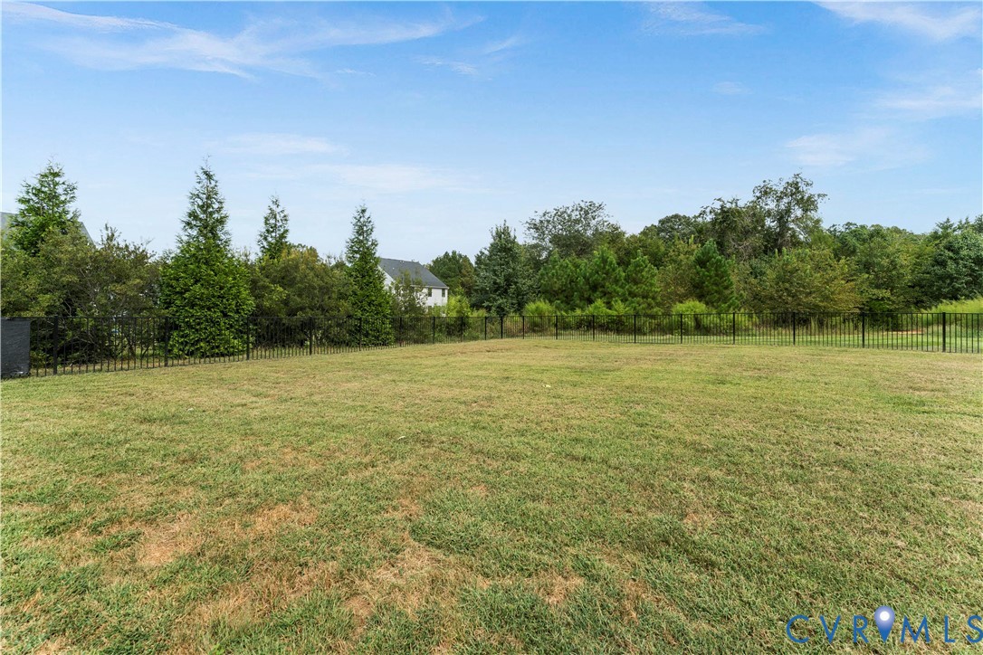Expansive lawn with perimeter fencing and mature trees