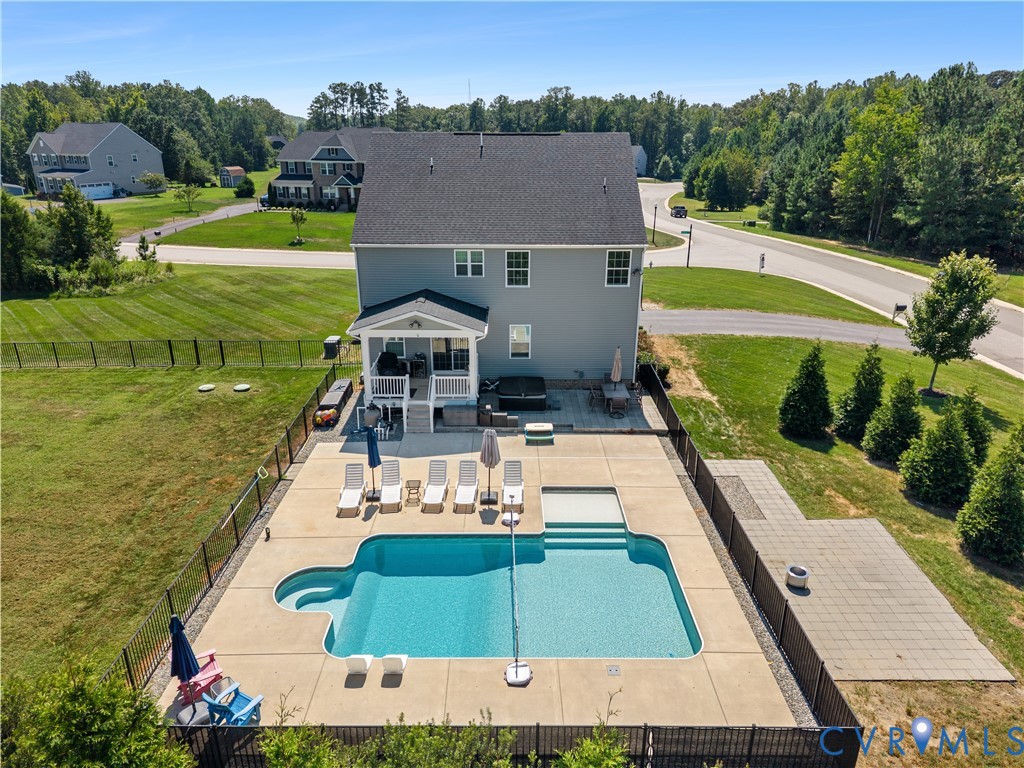 Expansive backyard oasis featuring a resort-style in-ground pool with sun lounging deck, mature landscaping with privacy plantings, and manicured lawn
