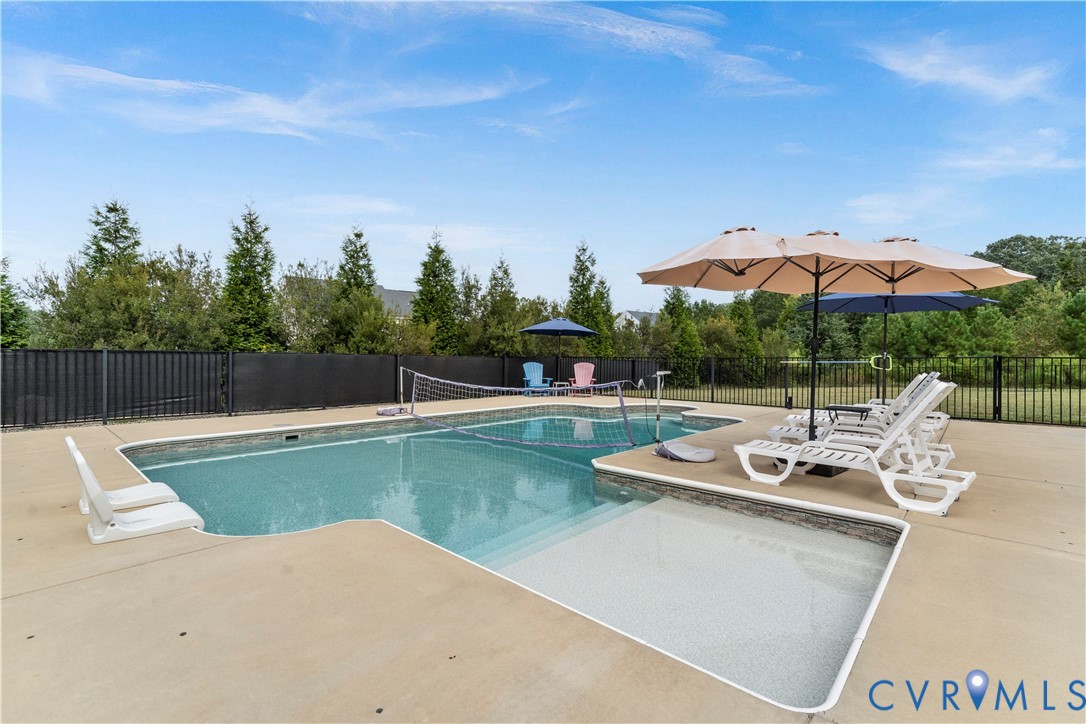 Lagoon-style swimming pool with an integrated shallow sun shelf, surrounded by a concrete deck