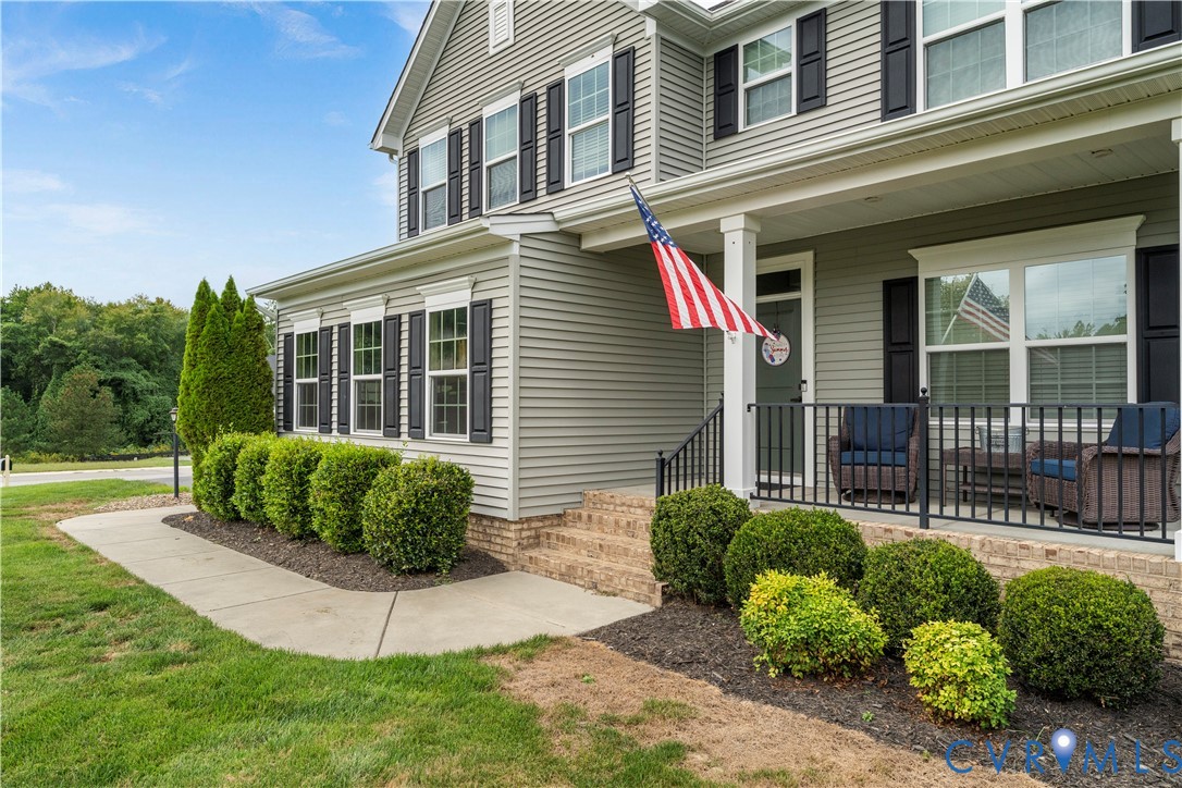 Siding exterior with contrasting dark window shutters, covered front porch, and brick foundation