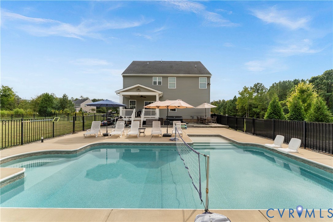 Expansive backyard featuring a built-in swimming pool, integrated steps, and a surrounding concrete patio